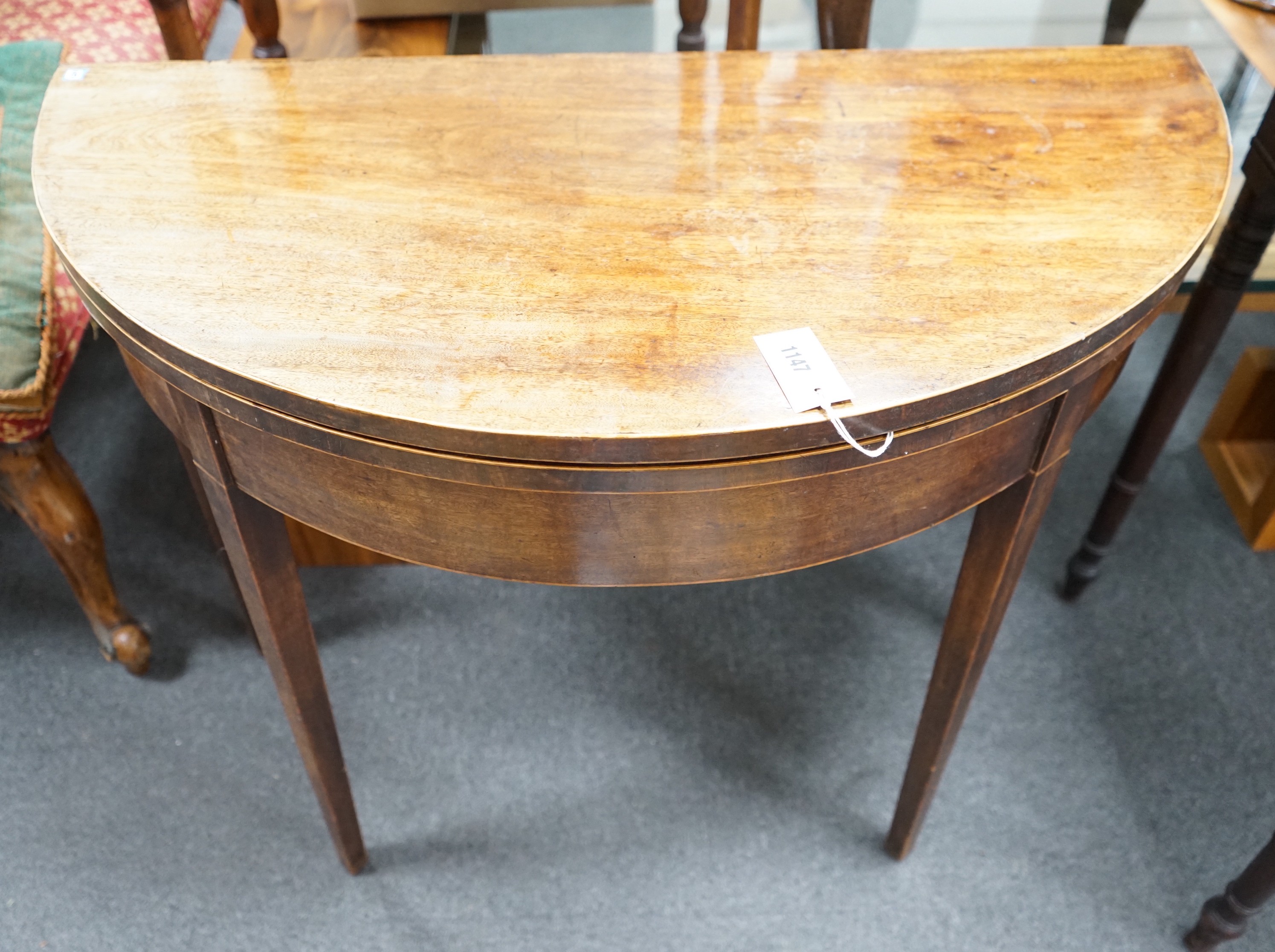 A George III mahogany and boxwood strung D shaped folding card table, width 91cm, depth 45cm, height 74cm